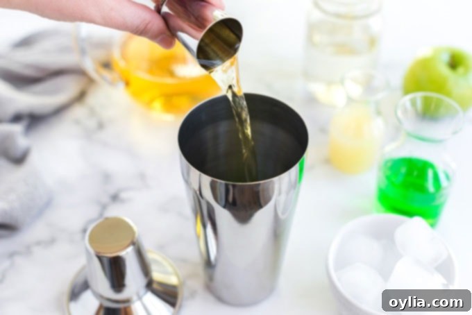 pouring apple juice into a cocktail shaker