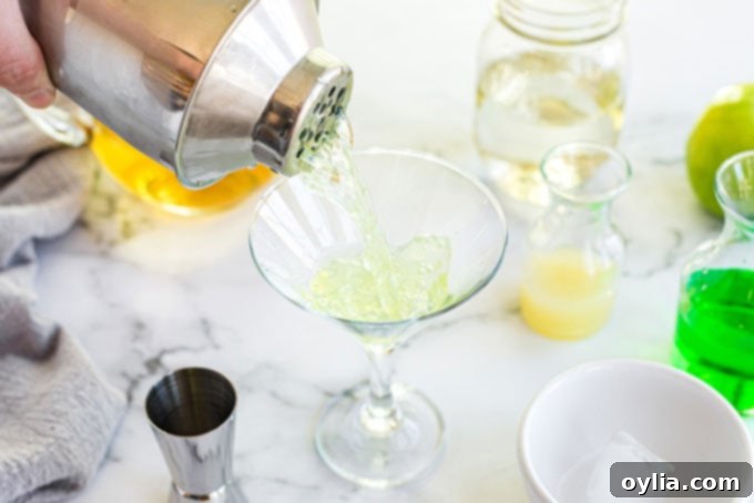 pouring shaken appletini into martini glass