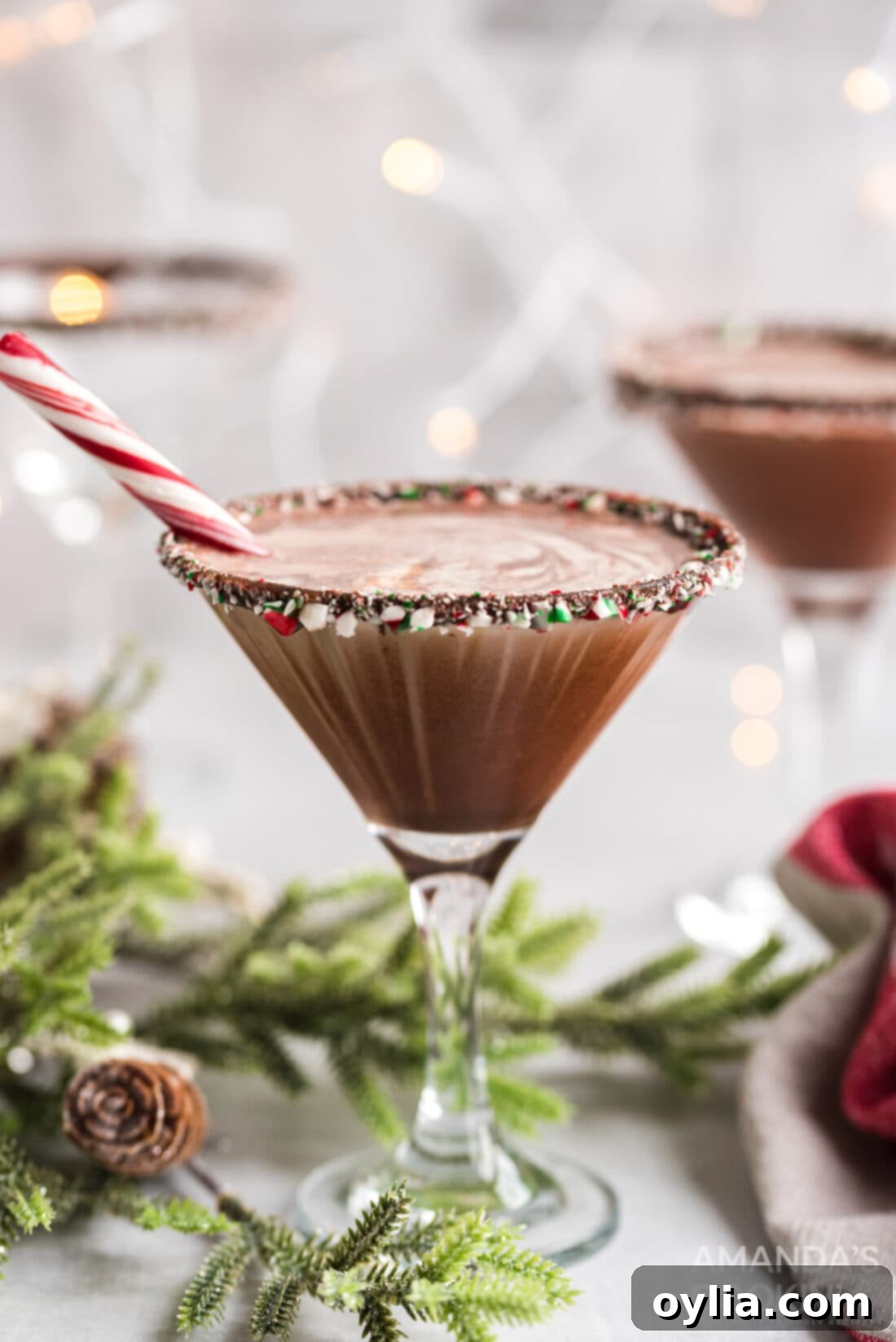 Close-up of a festive chocolate peppermint martini with a candy cane rim, adorned with a swirl of cream.