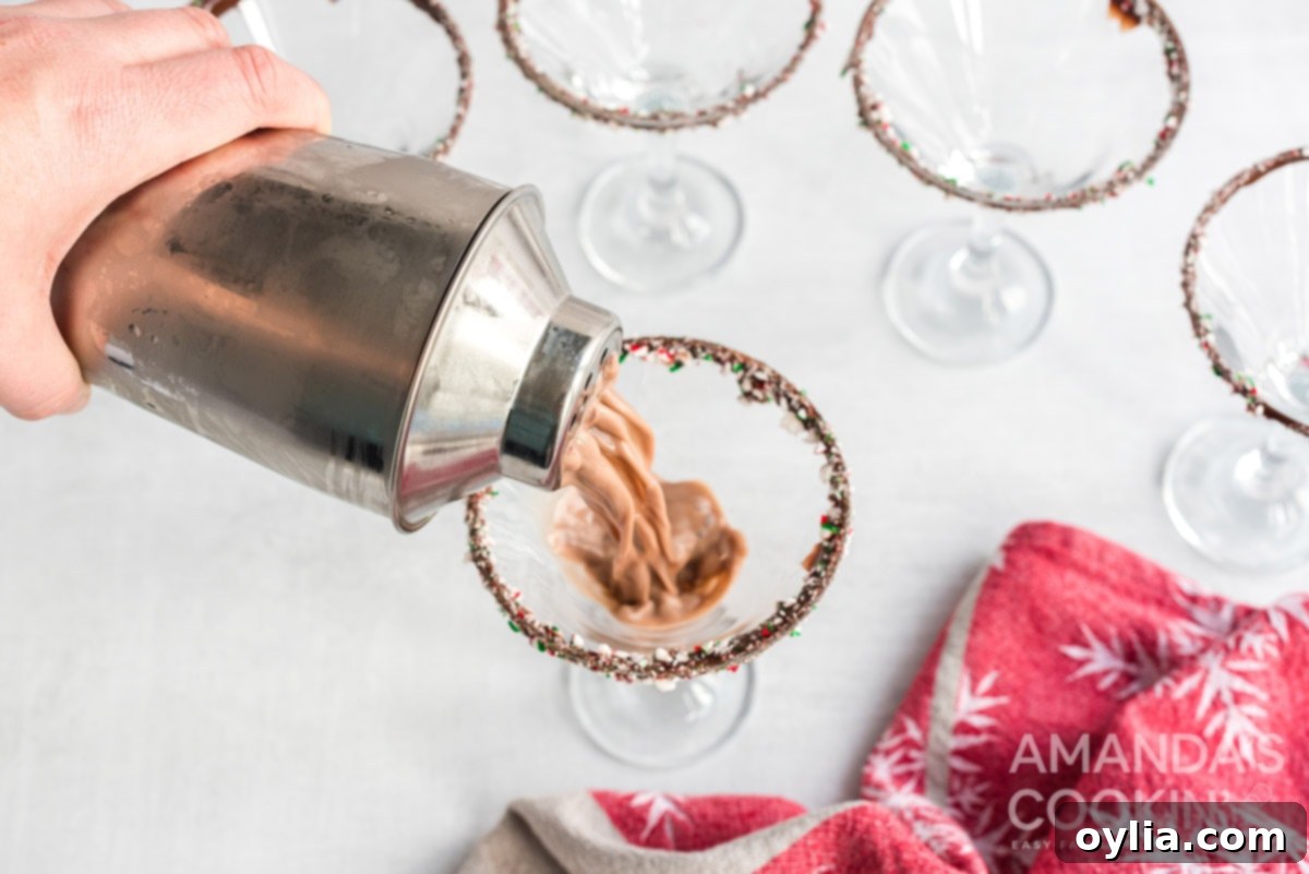 Pouring the freshly shaken chocolate peppermint martini into the chocolate and peppermint rimmed martini glass.