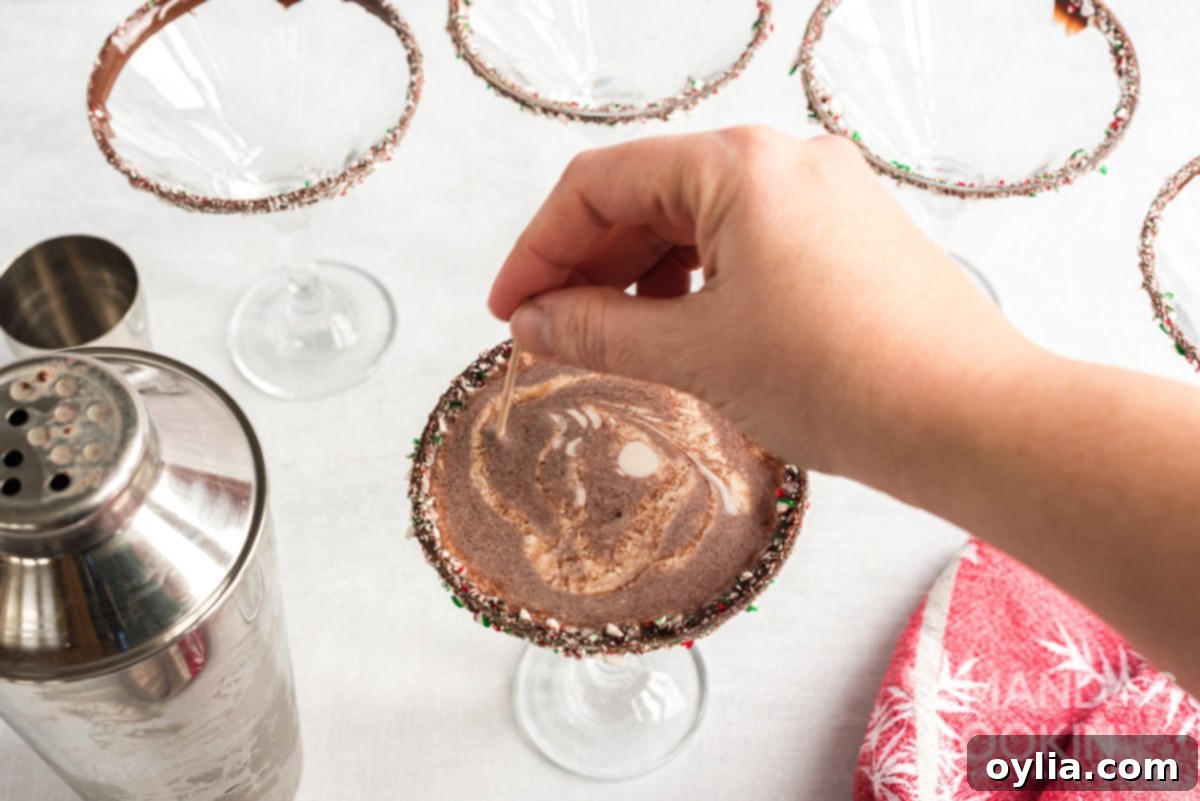 Using a toothpick to swirl the cream garnish on top of the chocolate peppermint martini for an artistic touch.