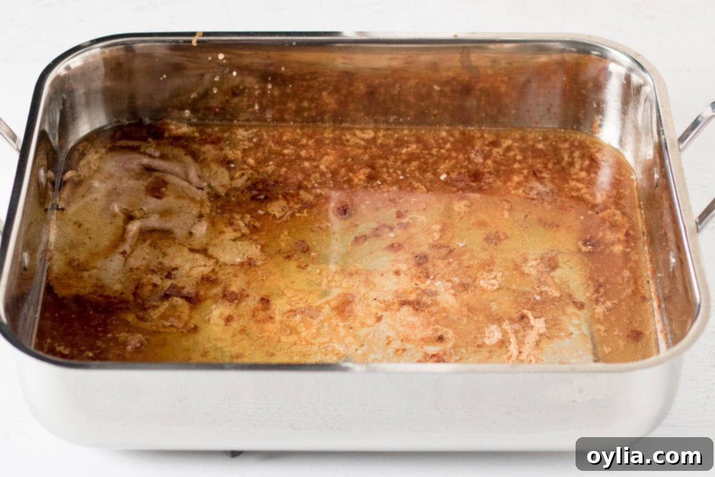 Roasting pan filled with rich turkey drippings after removing the roasted turkey