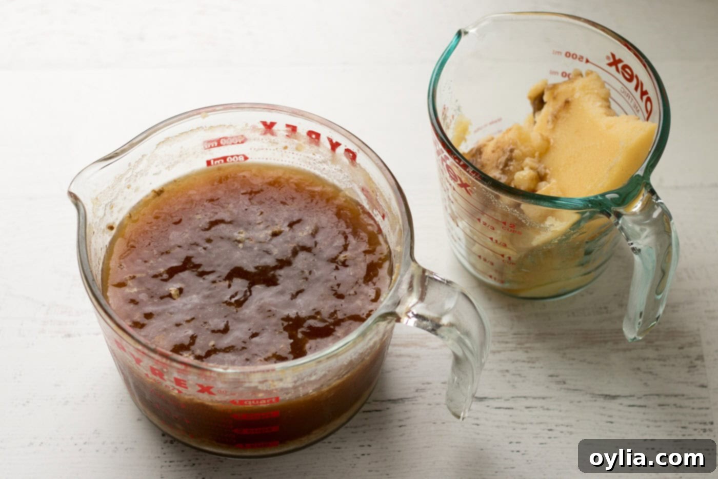 Two liquid measuring cups, one with skimmed fat and one with reserved turkey drippings for gravy