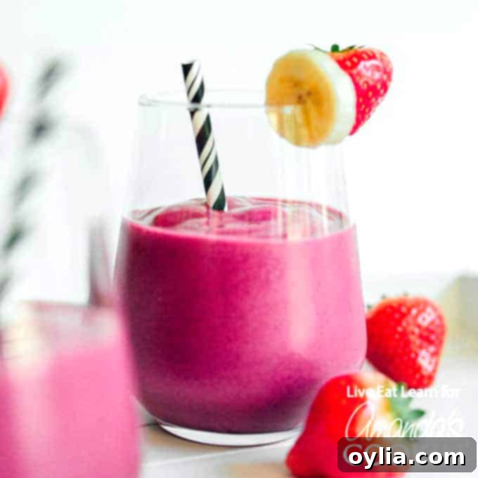 A glass of pink beet smoothie on a wooden surface, showing its creamy texture and rich color.