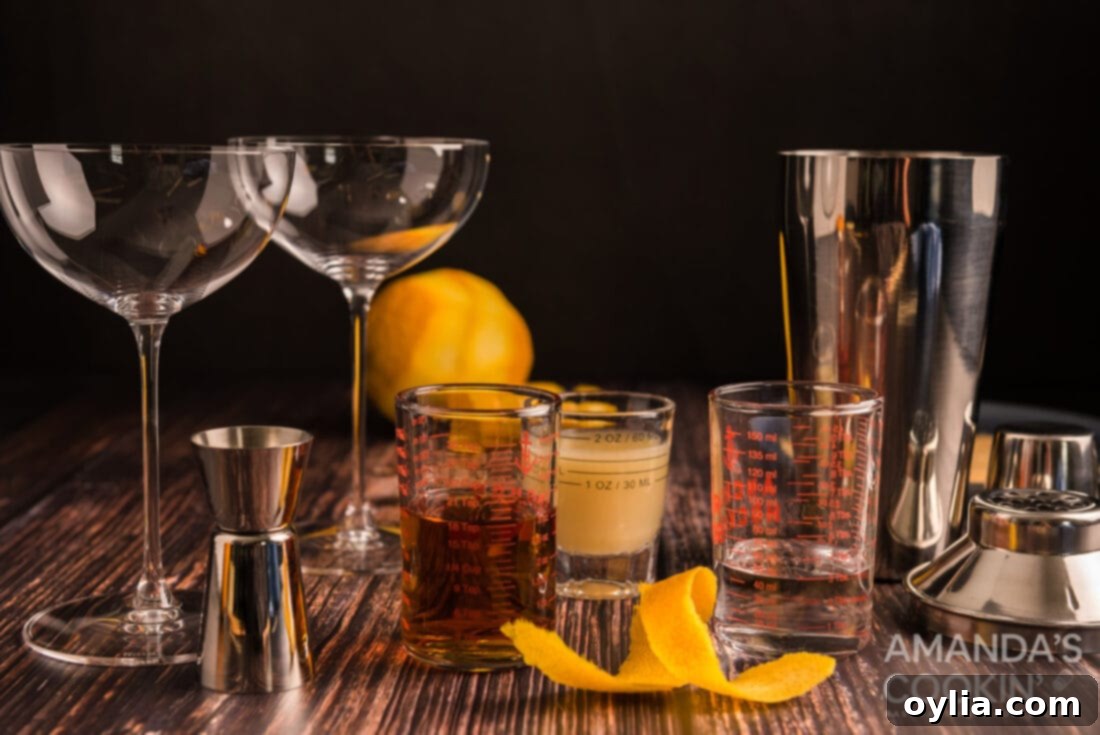 Ingredients for making a Sidecar cocktail: a bottle of brandy, triple sec, lemons, and a jigger on a wooden surface.