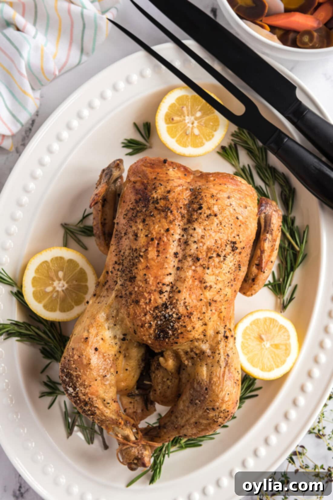 Roasted Chicken on a platter with carving utensils to the side