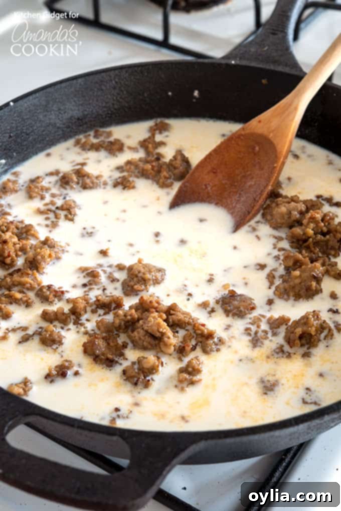 Creamy sausage gravy simmering and thickening in a skillet, ready to be seasoned