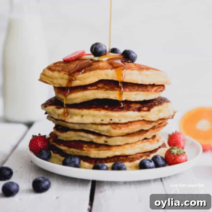 A beautiful plate of stacked buttermilk pancakes adorned with fresh blueberries, ready for syrup.