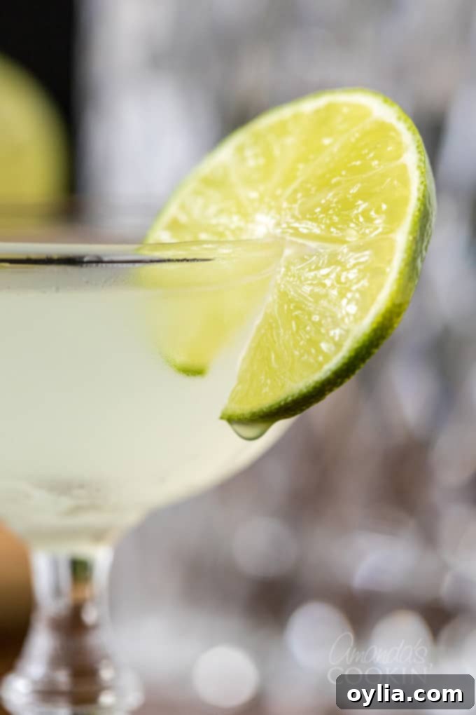 close up of gimlet cocktail in coupe glass with lime wheel garnish