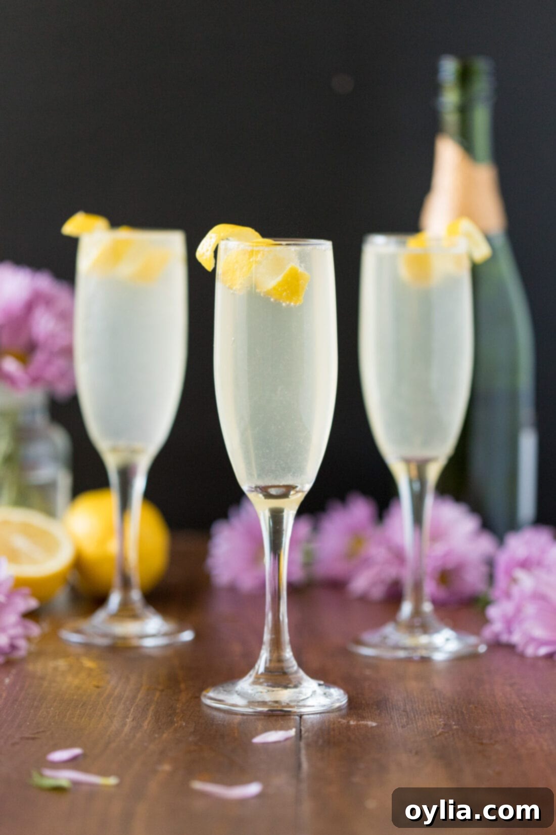 Elegant French 75 Cocktails for Any Occasion Three French 75 cocktails lined up, each garnished with a lemon twist, ready to be served