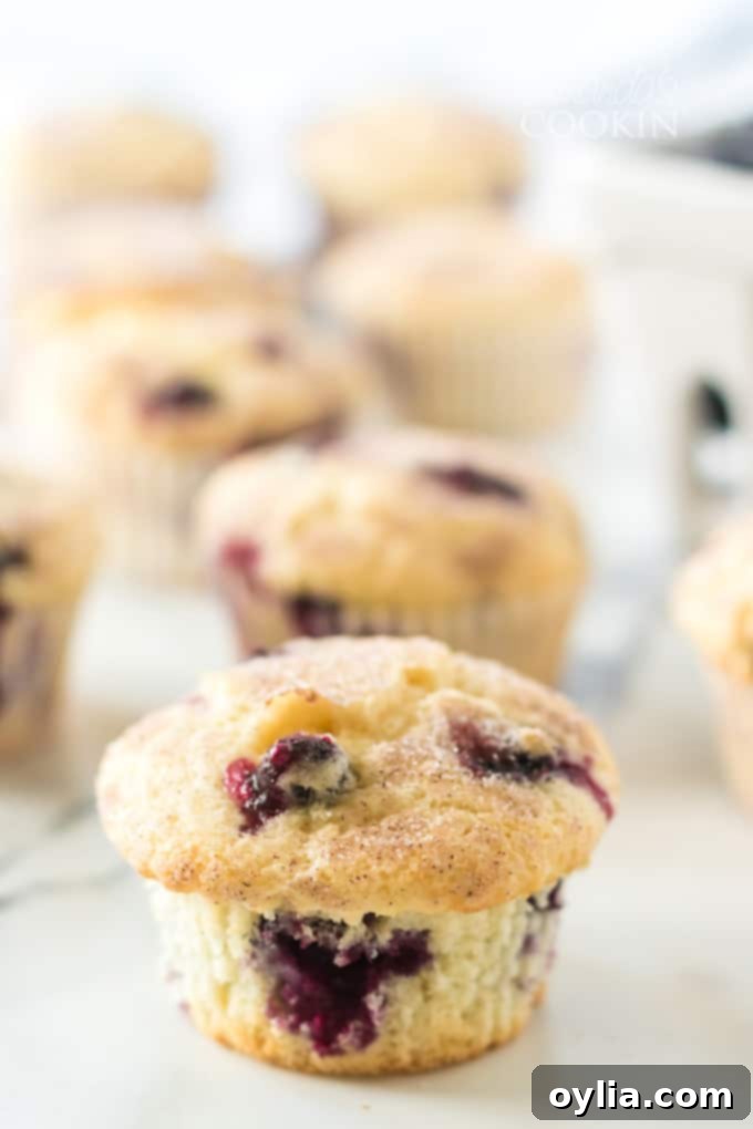 Several golden brown blueberry muffins fresh out of the oven, some with melted butter