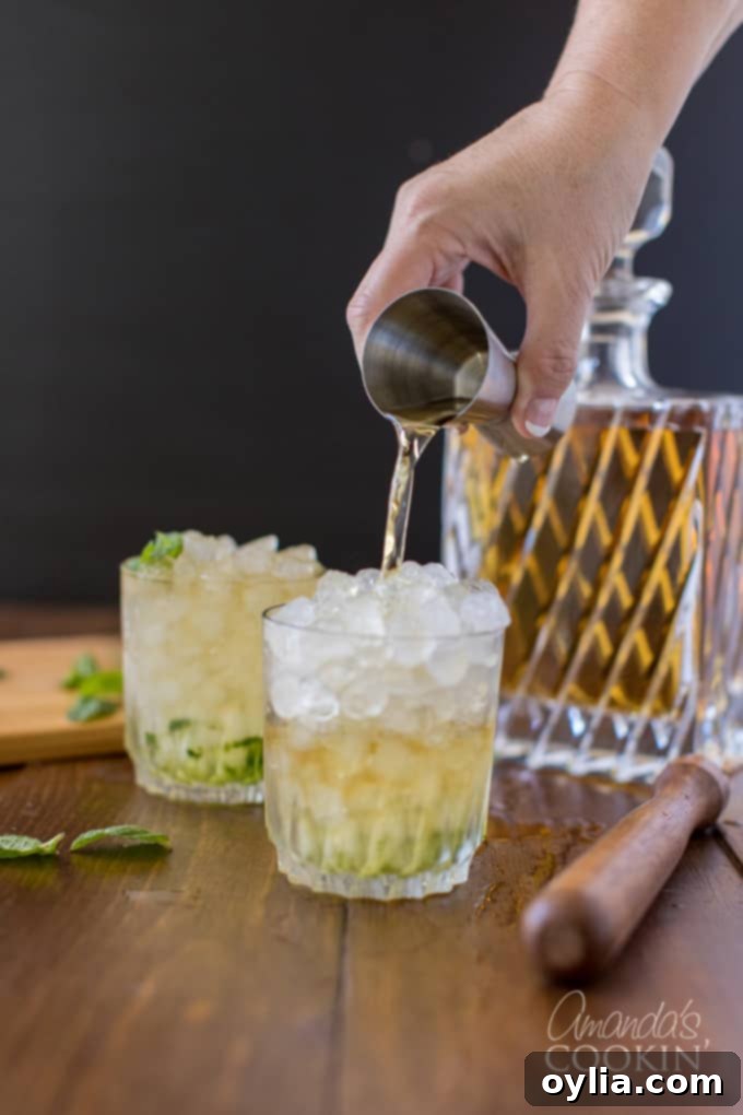 pouring bourbon whiskey from shot glass into highball glass