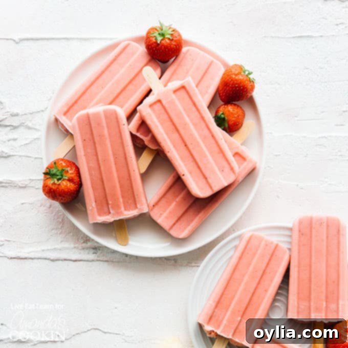 Several homemade strawberry banana popsicles arranged artfully on a plate.