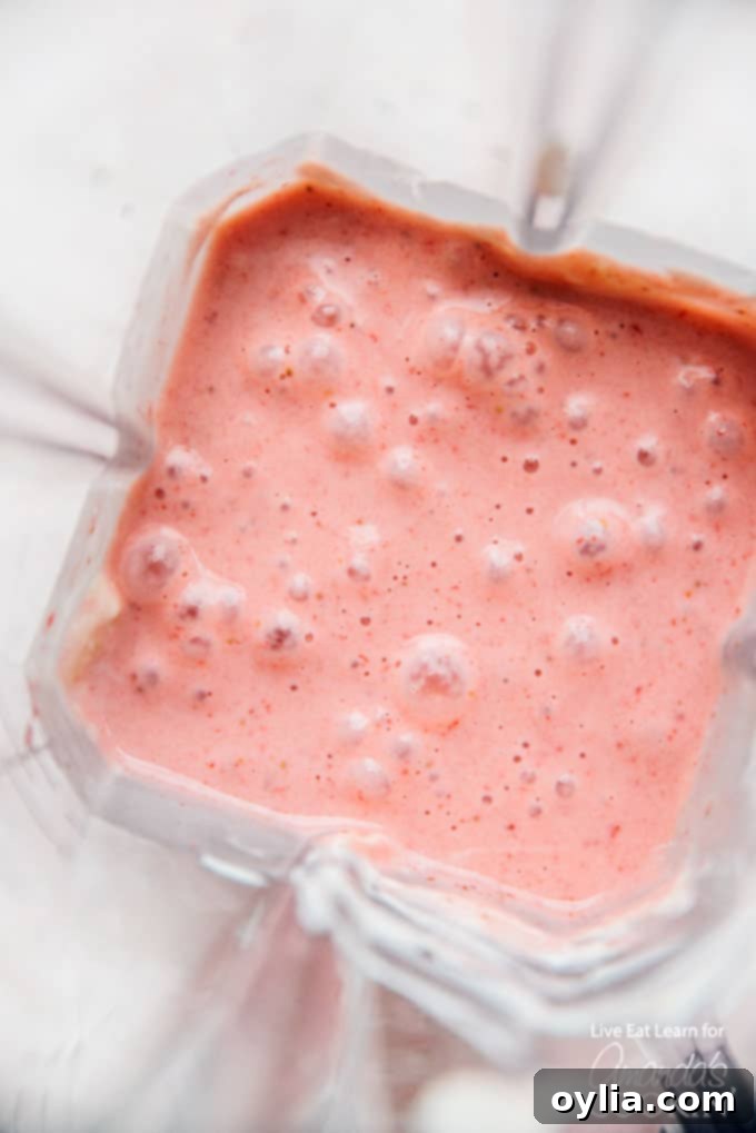 Strawberry banana smoothie mixture blending in a high-speed blender.