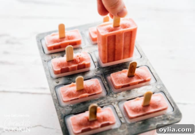 Popsicle mold filled with strawberry banana mixture, with sticks inserted.