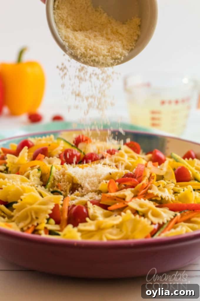 parmesan cheese being sprinkled over finished pasta primavera
