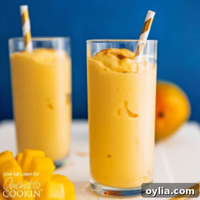 A mango lassi is a delicious yogurt and mango smoothie using Indian spices. This mango lassi smoothie is a sweet treat that's totally delicious. #mangolassi #mangolassismoothie #smoothierecipes #sweetsmoothies #mangosmoothie #amandascookin glass of Mango smoothie with straw