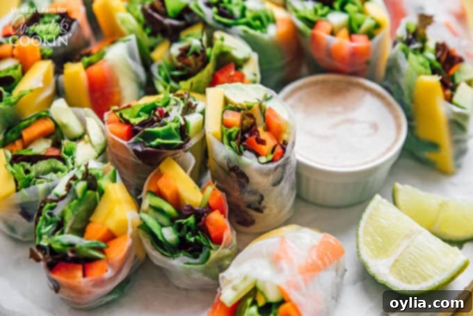 Platter of vegetable spring rolls, cut in half, served with a bowl of creamy almond dipping sauce and fresh lime wedges, ready to be enjoyed.