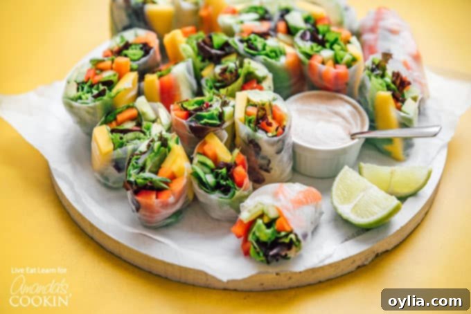 A plate of freshly rolled vegetable spring rolls, showcasing their neatly wrapped appearance and colorful fillings, served with dipping sauce.