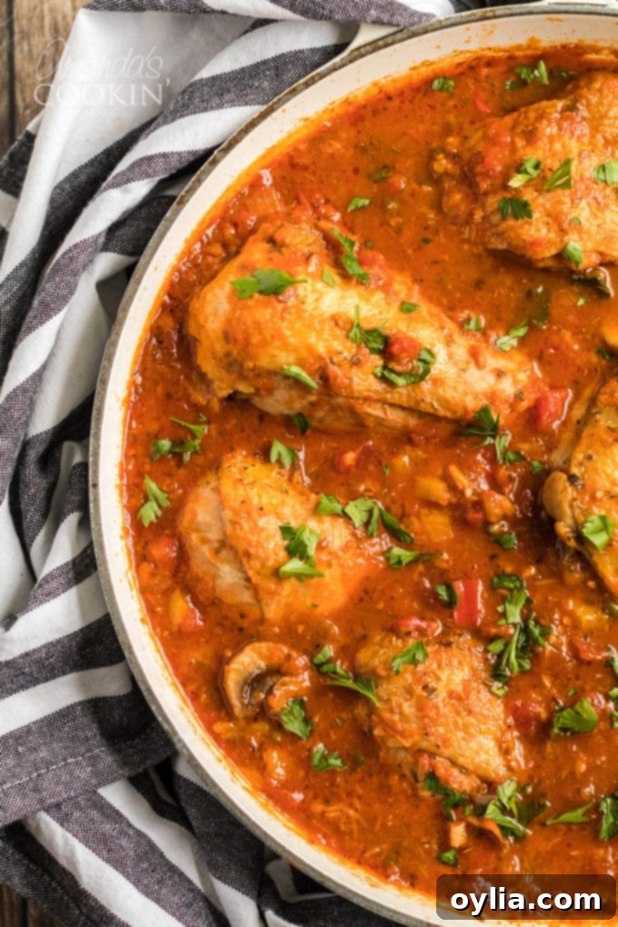 Close-up of bubbling Chicken Cacciatore stew with chicken and vegetables in a pan.