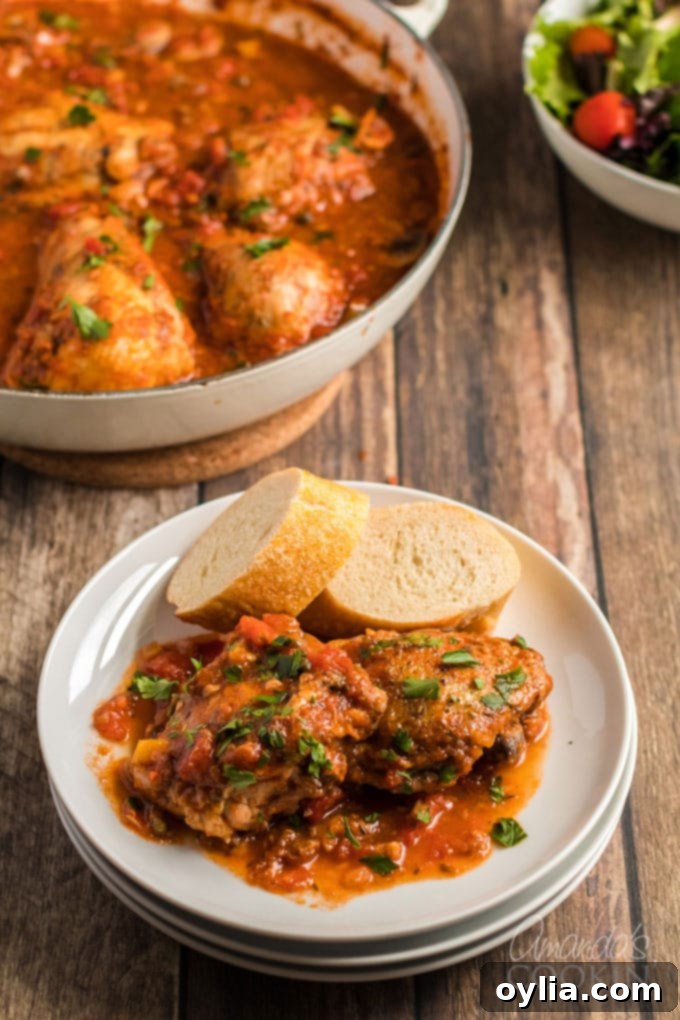 A generous serving of Chicken Cacciatore on a plate, garnished with fresh herbs and served with crusty bread.