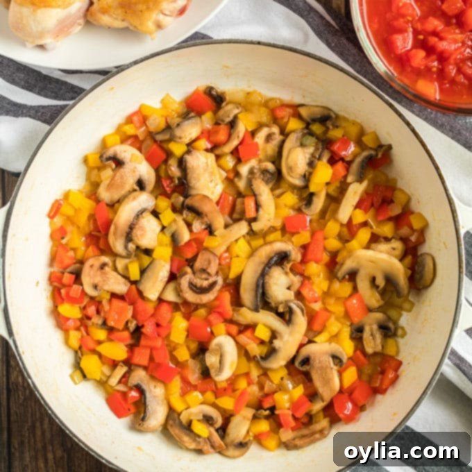 A colorful mix of bell peppers, onions, and mushrooms sautéed until tender in a pan.