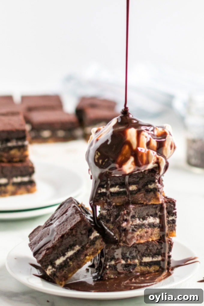 Stack of Slutty Brownies with a scoop of melting vanilla ice cream and chocolate syrup dripping over the top.