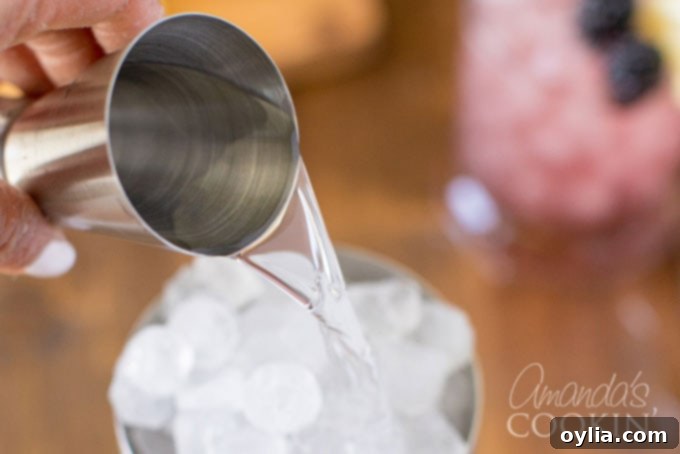 Pouring gin into a cocktail shaker filled with ice, illustrating the first step of mixing a Bramble cocktail.