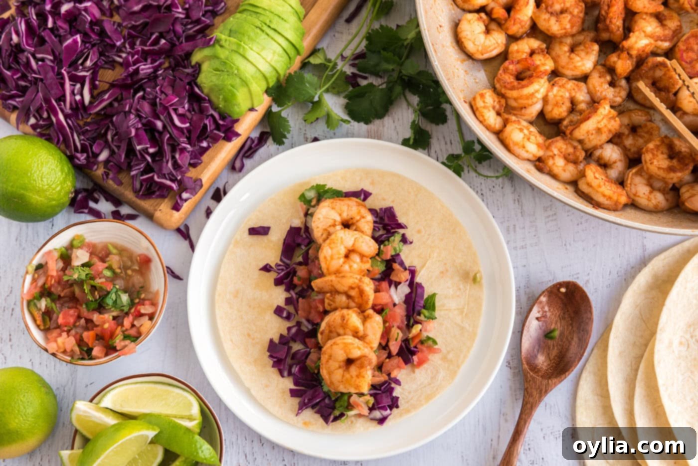 Finished shrimp tacos beautifully plated with cabbage, avocado, and fresh salsa