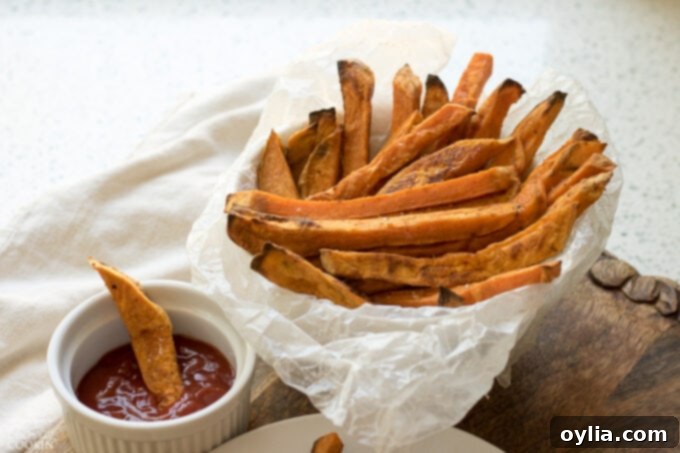 A serving of crispy sweet potato fries presented with a small ramekin of ketchup.