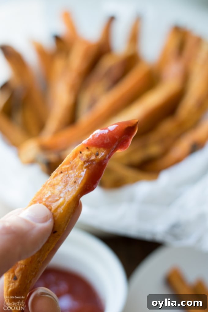 A single crispy sweet potato fry dipped in ketchup, showcasing its perfect texture.
