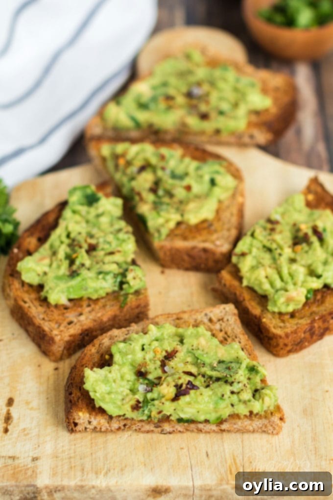 Slices of perfectly prepared avocado toast on a rustic cutting board, garnished with red pepper flakes and fresh cilantro.
