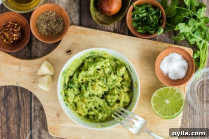 Close-up of mashed avocado in a small bowl, with a fork resting in it, ready for seasoning.