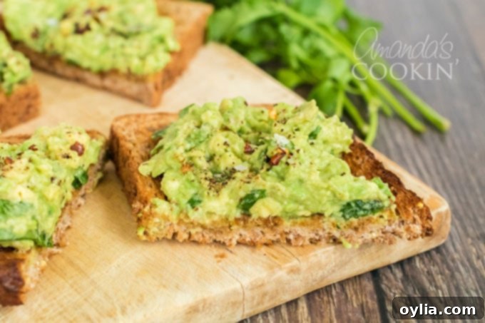 A finished avocado toast slice, garnished with red pepper flakes and cilantro, with more fresh cilantro in the background.