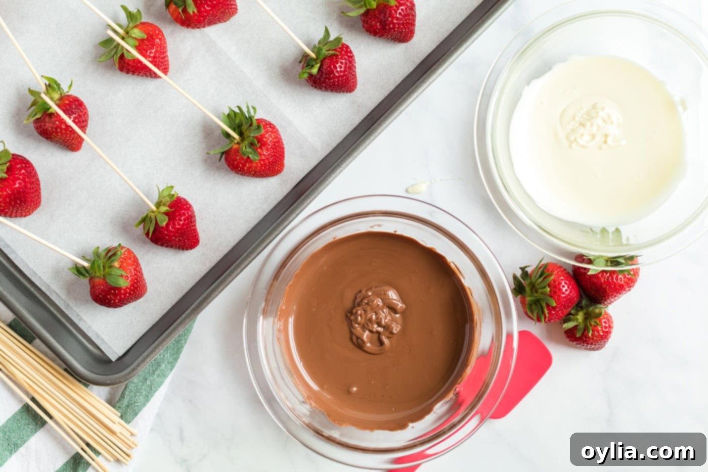 strawberries skewered on a pan and a bowl of melted chocolate