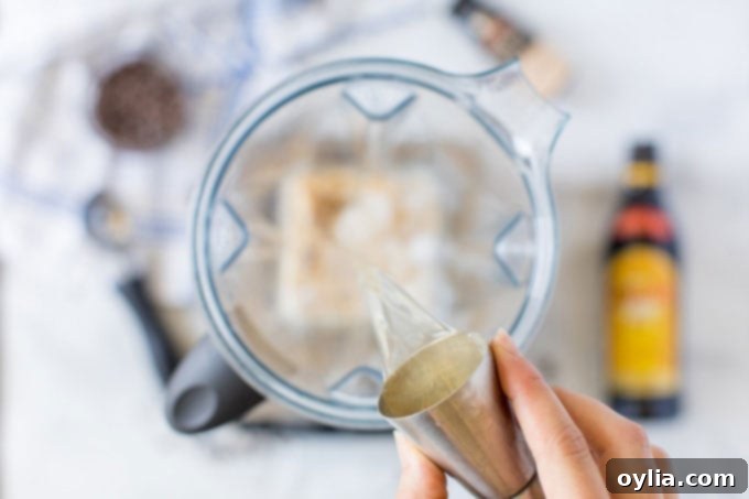 Adding vodka and other ingredients to a blender for a Frozen Mudslide cocktail.