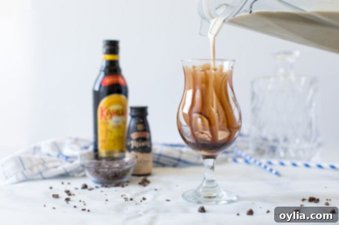 Pouring the creamy Frozen Mudslide mixture from a blender into a chocolate-drizzled glass.