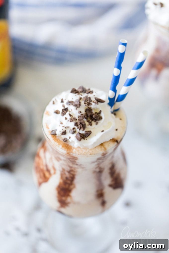 A chilled hurricane glass containing a perfectly blended Frozen Mudslide, with two straws for sharing.