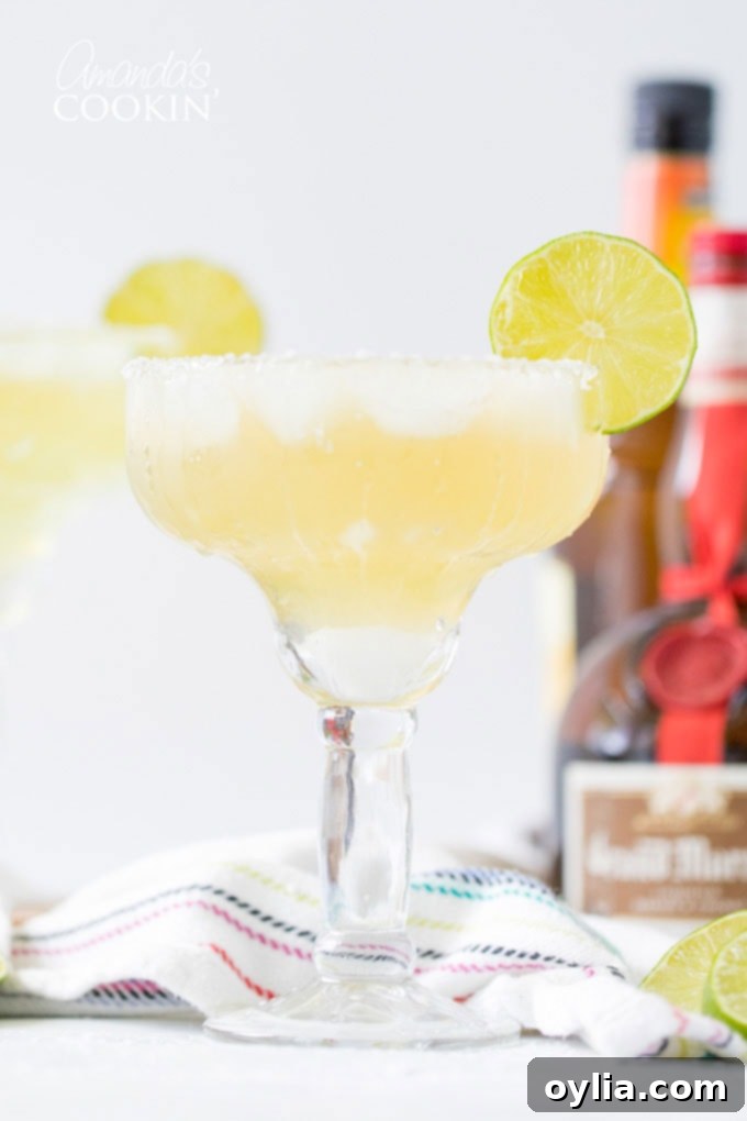 margarita on the rocks in a glass with a lime garnish on a wooden table