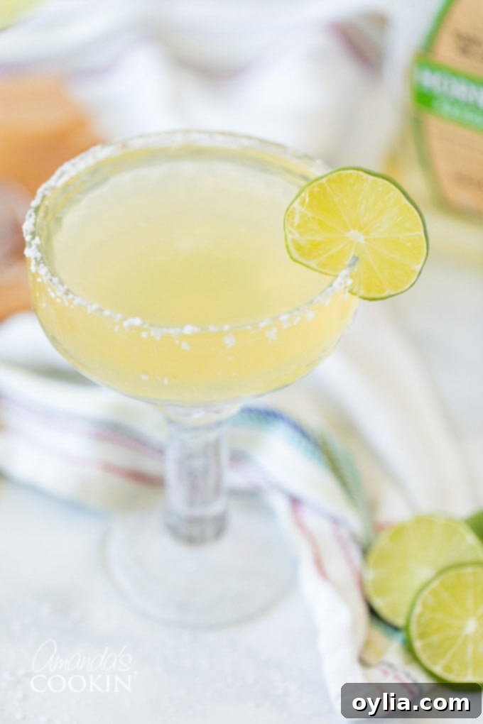 Margarita served without ice in a coupe glass with a lime garnish and salt rim