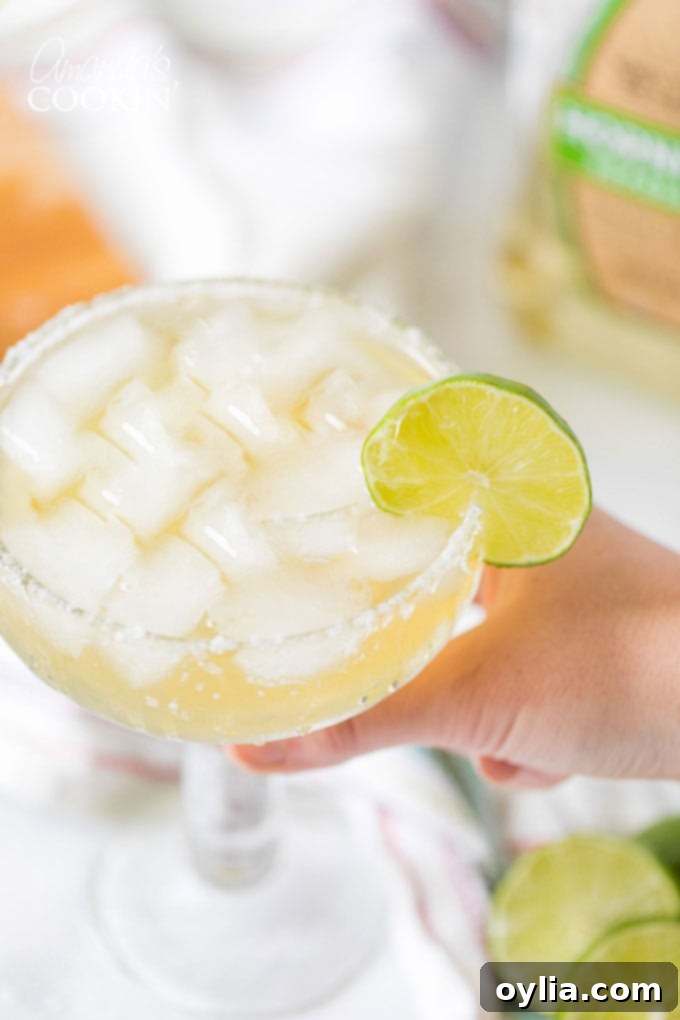 hand holding a margarita on the rocks with a lime garnish