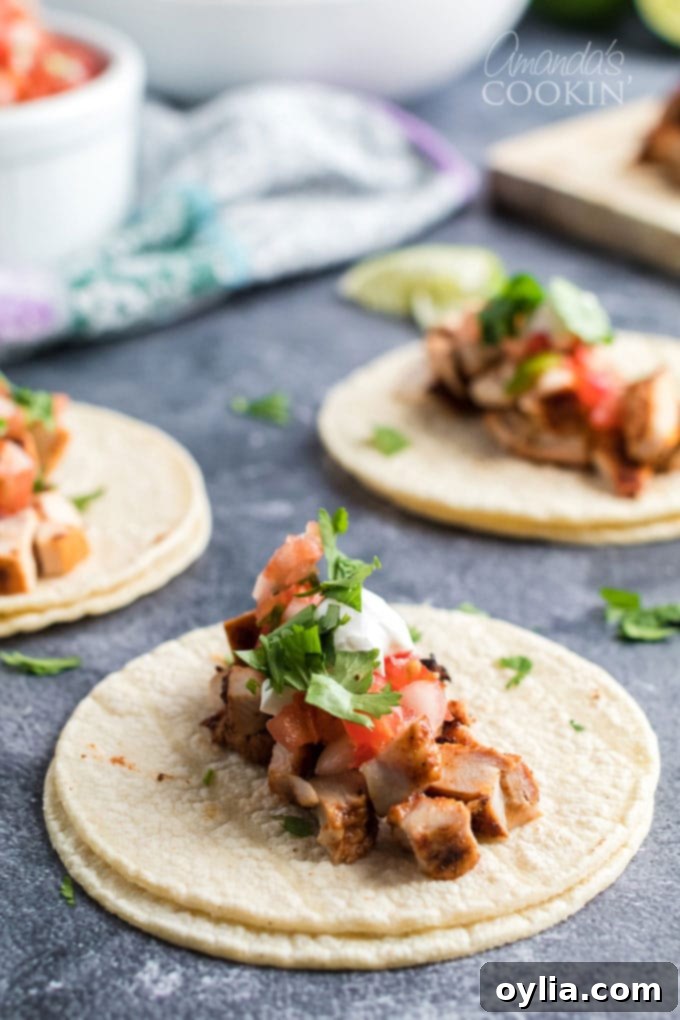 chicken taco ingredients piled in three corn tortillas