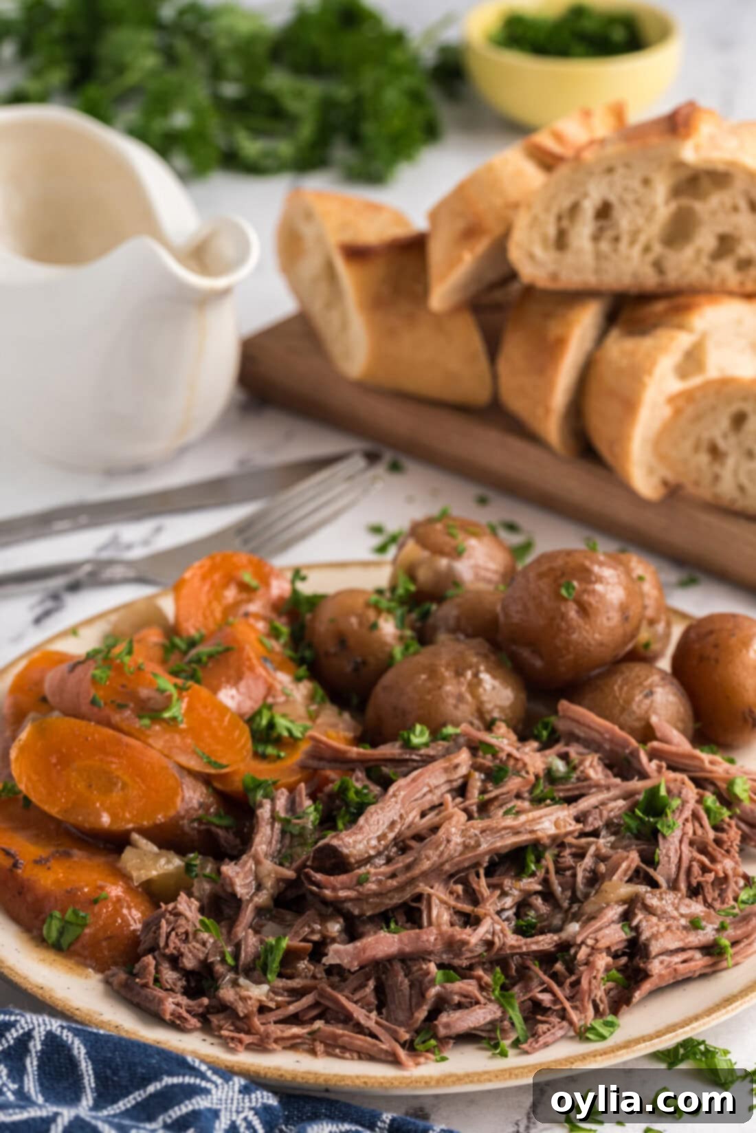 Shredded Crockpot Roast Beef on a platter with potatoes and carrots