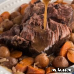 gravy pouring on crockpot roast beef on a platter