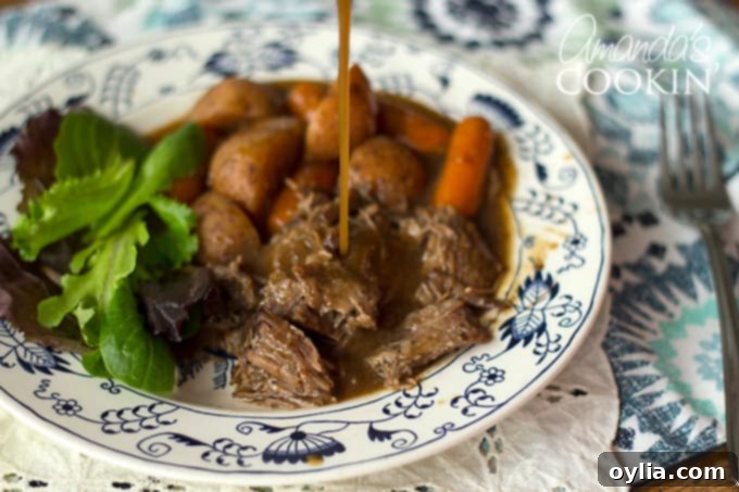 Gravy pouring onto crockpot roast beef and carrots