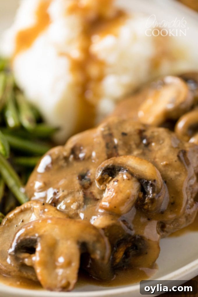 Mushrooms on top of Salisbury steaks with gravy, ready to be served