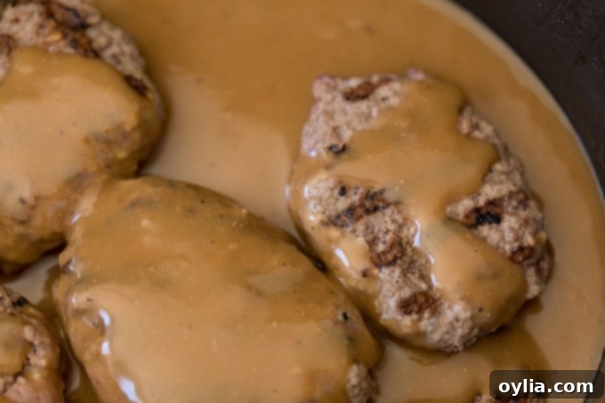 Salisbury steak simmering in gravy in a skillet