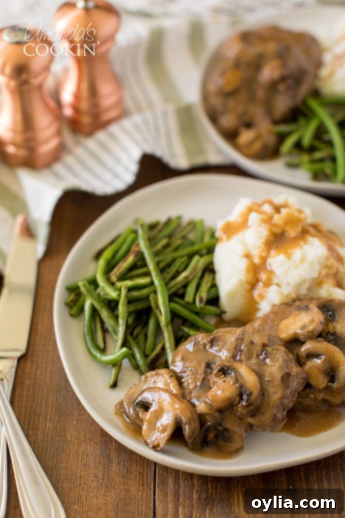 A plate of Salisbury steak with mashed potatoes and gravy on a dining table