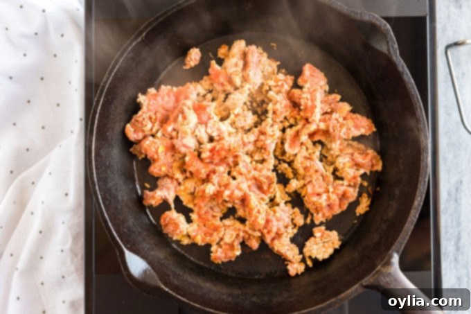 ground pork sausage being browned in a cast iron skillet