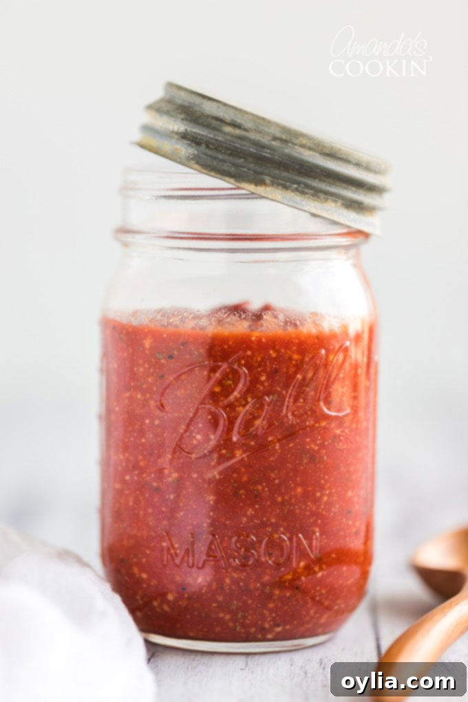 Freshly made homemade pizza sauce stored in a glass jar, perfect for freezing.